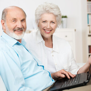 lachendes älteres ehepaar am laptop